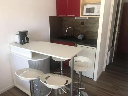 - une petite cuisine avec un comptoir blanc et des tabourets dans l'établissement Studio très beau quartier le Ponant avec piscine Résidence Port Vincent, à La Grande Motte
