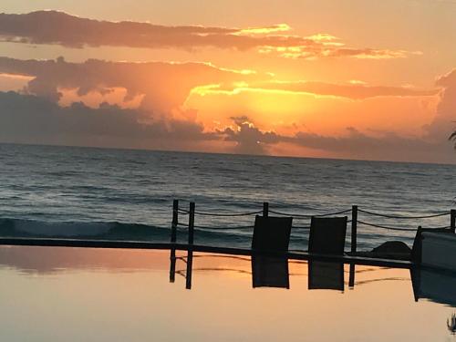 a sunset over the ocean with a fence at BOF Apartments Cancun in Cancún