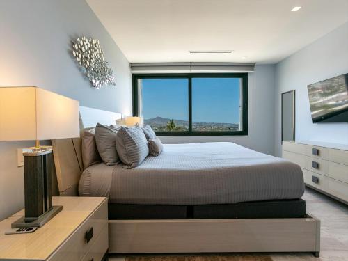 Un dormitorio con una cama y una ventana grande. en Dream At Cardinal Living, en Cabo San Lucas