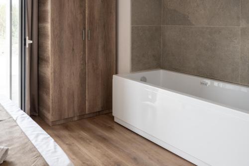 a white bath tub in a bathroom with wooden cabinets at Bellavista Kamarina Resort in Scoglitti