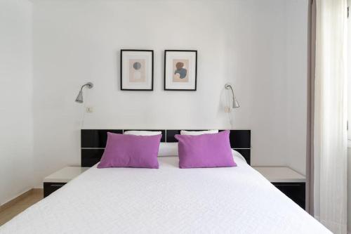 1 dormitorio con 1 cama grande con almohadas moradas en Casa Alba, en Puerto del Carmen