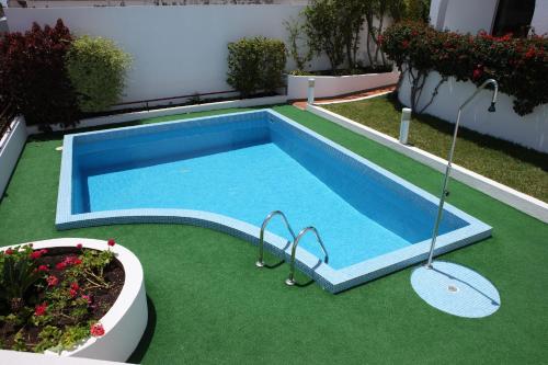 a small swimming pool with green grass and plants at Canico Bay Apartments in Caniço