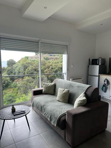 a living room with a couch and a large window at Résidence les Moulins-appartements privatifs in Olmeto
