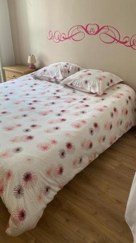 - un lit avec une couverture blanche et des fleurs dans l'établissement Le 6 Magnifique appt Bagnères-de-Bigorre 3étoiles, à Bagnères-de-Bigorre