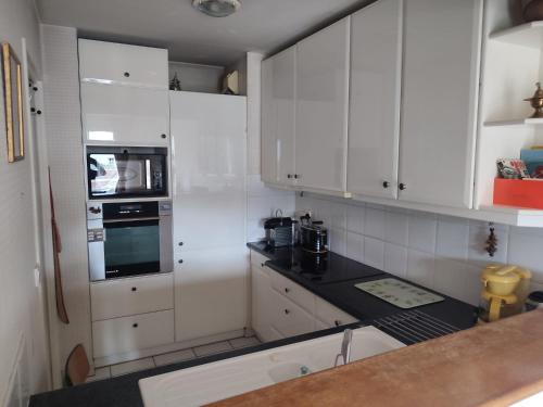 une cuisine avec des armoires blanches et un comptoir noir dans l'établissement Appartement Orsay Grand Paris, à Orsay