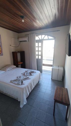 a bedroom with a white bed and a wooden ceiling at Pousada da Ale in Ilhéus