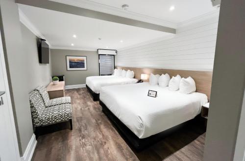 a hotel room with two beds and a chair at Colonial Hotel & Suites in Grand Bend
