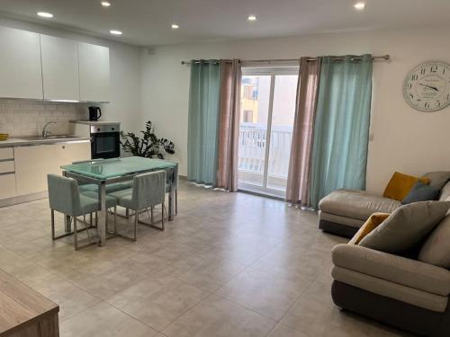 a kitchen and a living room with a table and a couch at Sea side view 2 bedroom apartment with terrace Beppe`s apartment in St Paul's Bay