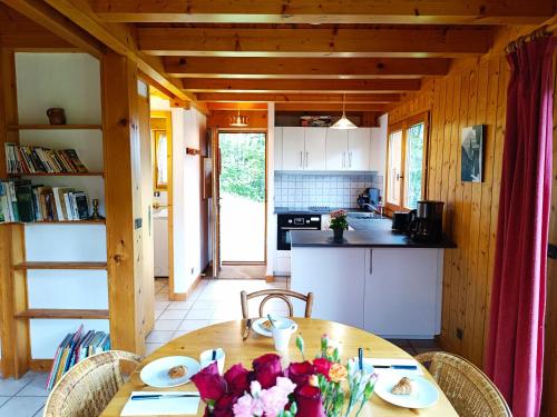 une cuisine avec une table en bois et des fleurs. dans l'établissement Le Mazot des Tacounets, à Saint-Gervais-les-Bains