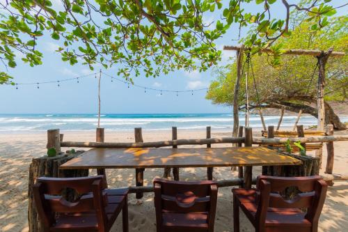 una mesa y sillas en una playa con un columpio en Casa Yosi, Beach Front Piece of Heaven, en San Juan del Sur
