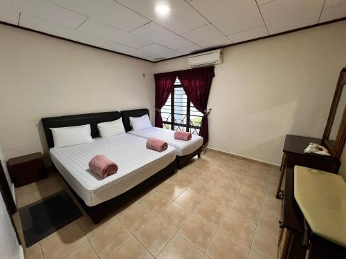 a bedroom with a bed with white sheets and pink pillows at Pool Villa 833 - Fong Homestay in Kampong Alor Gajah