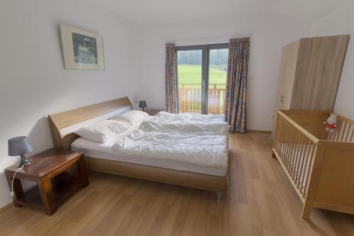 a bedroom with a bed and a window and a crib at Haus Johendre in Rennweg