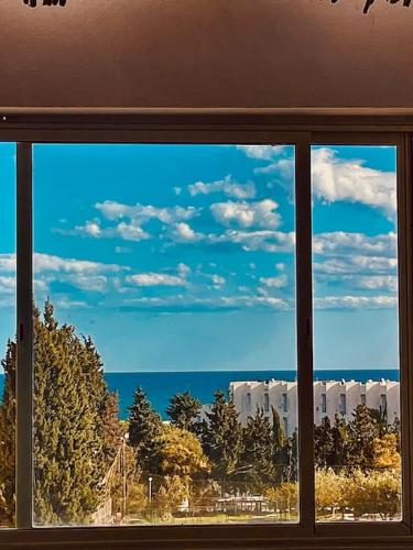 a window with a view of the ocean and trees at Vue sur Mer in Nabeul