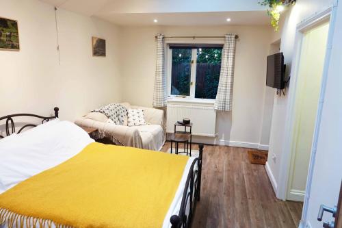 a bedroom with a bed and a couch at Holly Tree Hideaway in Milton Keynes