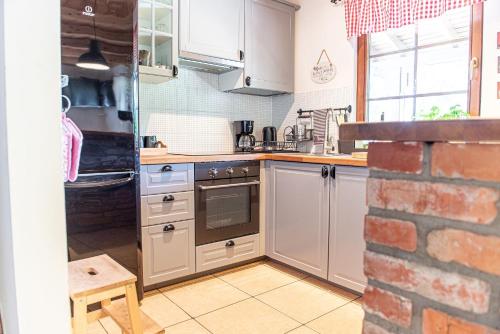 a kitchen with white appliances and a brick wall at Rajski Domek nad Jeziorem Radacz in Borne Sulinowo