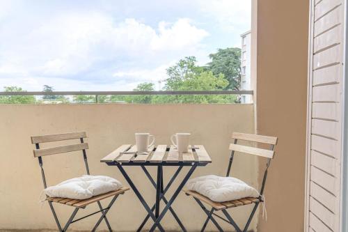 une table et deux chaises sur un balcon dans l'établissement Le Pressensé, idéal séjour pro ou familiale, à Vénissieux