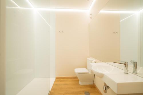 Un baño blanco con lavabo y espejo. en Mouritz Rooms, en Negreira