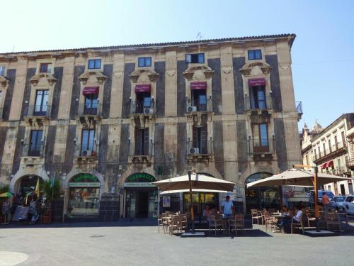 ein großes Gebäude mit Tischen und Sonnenschirmen davor in der Unterkunft Hotel Centrale Europa in Catania