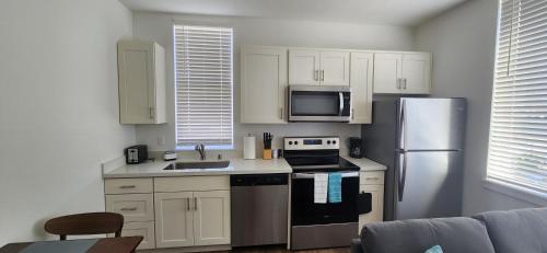 a kitchen with white cabinets and a stainless steel refrigerator at Urban Living: Stylish Apts in the Heart of Tacoma in Tacoma