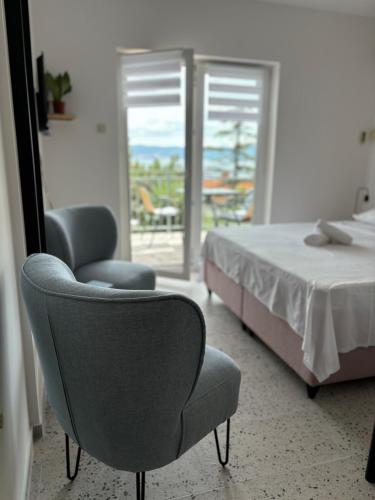 a bedroom with a bed and a chair and a window at Ema Rooms in Novi Vinodolski