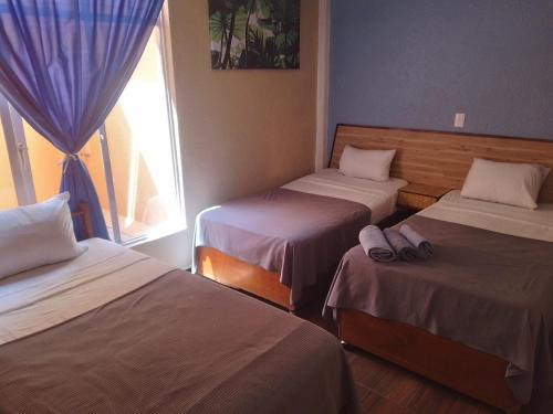 a room with three beds and a window at Hotel Los Diamantes in Orizaba