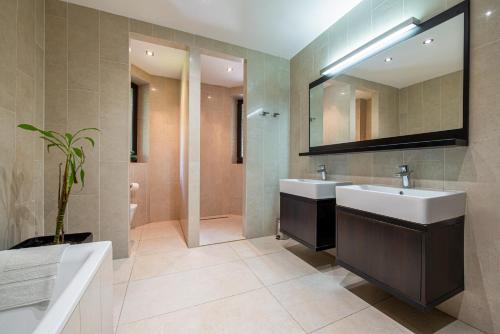uma casa de banho com 2 lavatórios, uma banheira e um espelho. em Chillgarden Apartments em Trenčín
