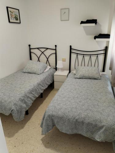 a bedroom with two beds with gray comforters at Apartamento Sol A air conditioning in Vecindario