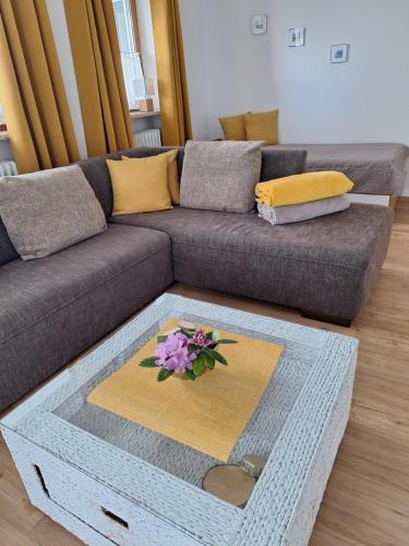 a living room with a couch with a table with flowers on it at Wohlfühlen am Waldrand in Thurmansbang
