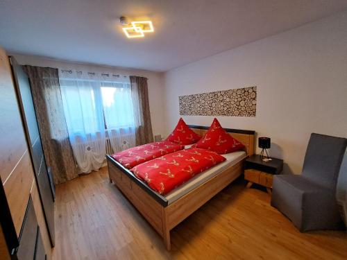 a bedroom with a bed with red pillows on it at Wohlfühlen am Waldrand in Thurmansbang