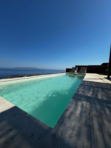 uma piscina com cadeiras e o oceano ao fundo em Thermyes Villas 3 em Kythnos