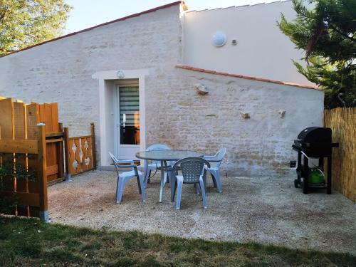 un patio avec une table, des chaises et un barbecue dans l'établissement Quatre As - Studio au calme, à Saint-Christophe