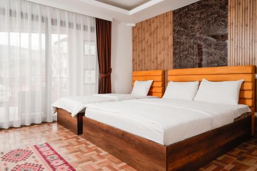 a bedroom with two beds and a large window at Denis Hotel in Prizren