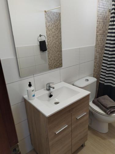a bathroom with a sink and a toilet and a mirror at Apartamento Sol A air conditioning in Vecindario