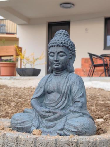 a statue of aitating buddha sitting in a garden at SunsetHouse Piešťany Country Tourist Lodge in Banka