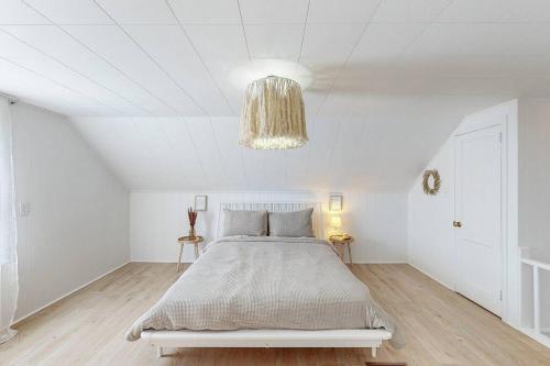 a white bedroom with a bed and a chandelier at End Zone Escape-Light and Bright HOF Village Home in Canton