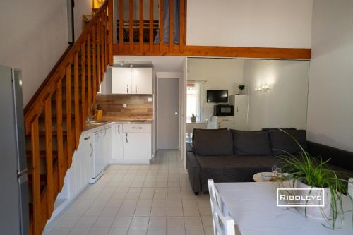 Il dispose d'une cuisine et d'un salon avec un canapé et un escalier. dans l'établissement Maison climatisée avec WIFI à 300m de la mer, à Vias