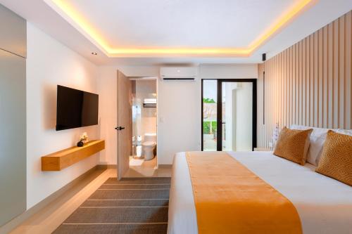 a bedroom with a bed and a tv on a wall at Coralia Boutique Hotel Cozumel in Cozumel