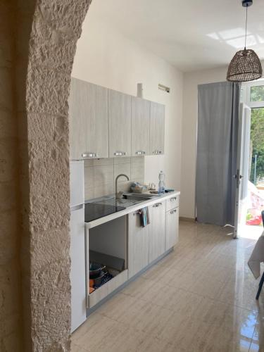 Una cocina con gabinetes blancos y un fregadero. en Villa Cosmo, en Alberobello