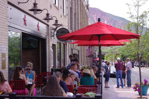 a group of people sitting at a restaurant under a red umbrella at Hotel Maxwell Anderson in Glenwood Springs