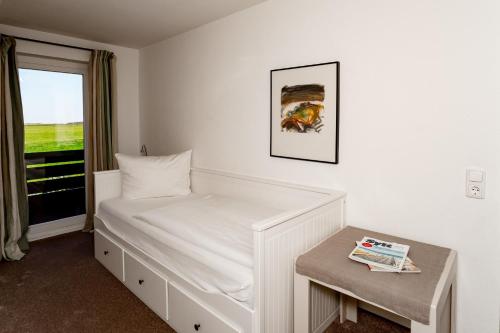 a small bedroom with a bed and a window at Sylter Seestern Haus Nösseblick in Morsum
