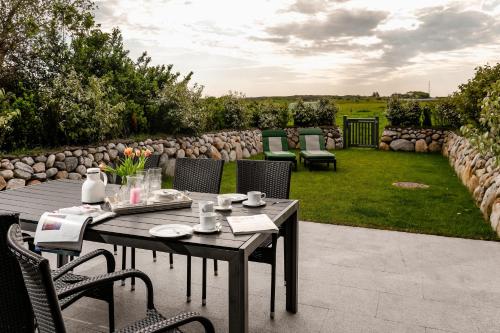 a patio with a table and chairs and a garden at Sylter Seestern Haus Nösseblick in Morsum