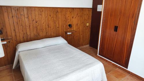 Cama pequeña en habitación con paredes de madera en Hostal Jadraza, en Zahara de los Atunes