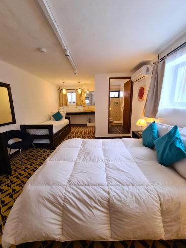 a bedroom with a large white bed with blue pillows at Posada El Capullo in Colonia del Sacramento