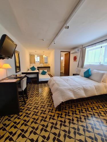 a bedroom with a large bed and a living room at Posada El Capullo in Colonia del Sacramento