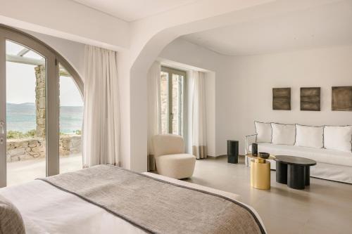 a bedroom with a bed and a view of the ocean at Grace Mykonos in Agios Stefanos