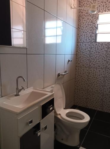 a bathroom with a white toilet and a sink at Pousada Santos lll, kitnet confortável com ar condicionado in Londrina