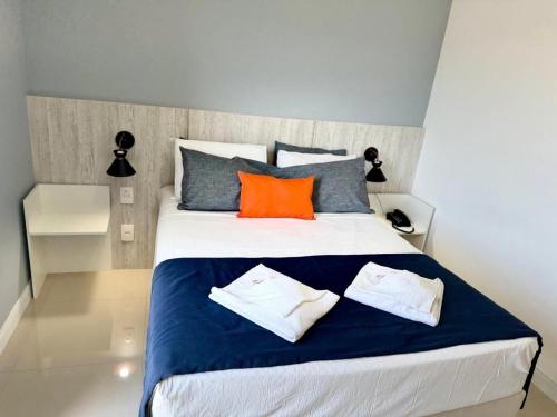 - une chambre dotée d'un grand lit avec des oreillers bleus et oranges dans l'établissement Flat 426 comodidade na Passagem em Cabo Frio, à Cabo Frio