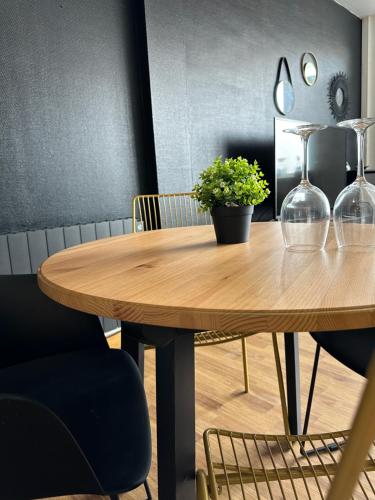 une table en bois avec deux verres à vin et une plante en pot dans l'établissement Appartement Citadelle 0, à Dunkerque