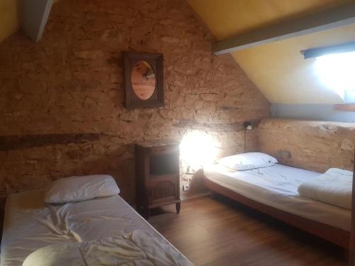 - une chambre avec 2 lits dans un mur en pierre dans l'établissement Charmante maison avec piscine partagée à Le Buisson-de-Cadouin, au Buisson de Cadouin