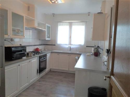 a kitchen with white cabinets and a window at MAISON de VACANCES in Seyresse